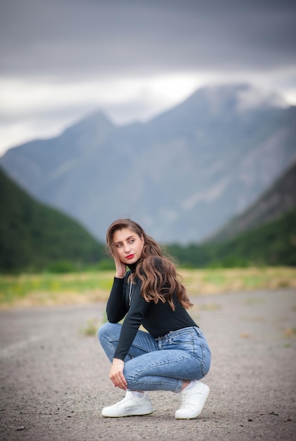 Beautiful young girl in jeans on the mountain