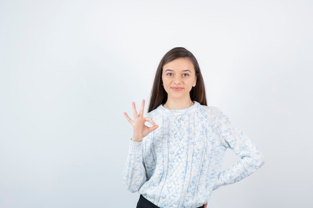 Beautiful young girl in knitted sweater standing and posing.