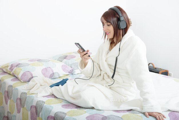 Beautiful young girl listening to music in her bed