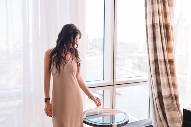 Beautiful young girl in a long dress in hotel room