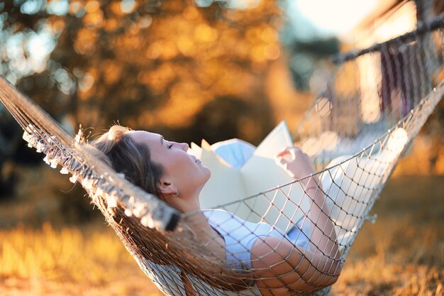 Beautiful young girl lying and reading a book in the autumn outdoors