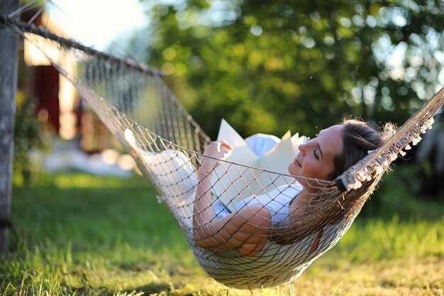 Beautiful young girl lying and reading a book in the summer outdoors