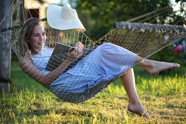 Красивая молодая девушка лежит и читает книгу летом на открытом воздухе
