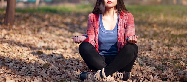 Beautiful young girl meditates in autumn park