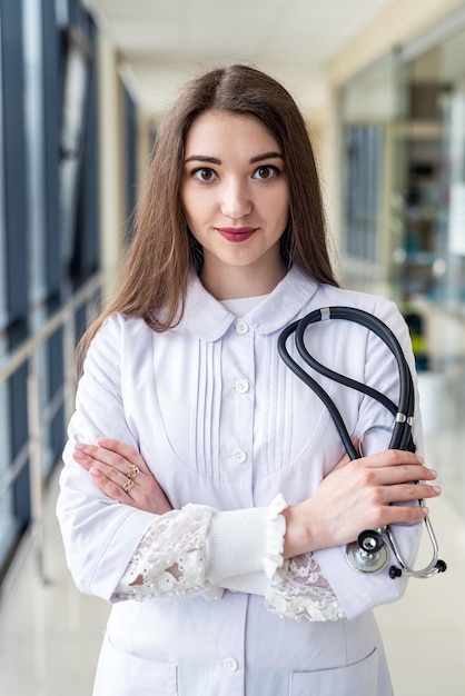 Beautiful young girl nurse is standing in special gown in the middle of the hospital corridor