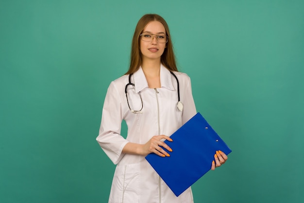 Beautiful young girl nurse or trainee doctor with blue folder and statoscope on a blue space 