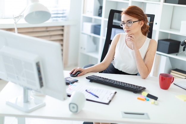 Beautiful young girl in the office working at the computer.