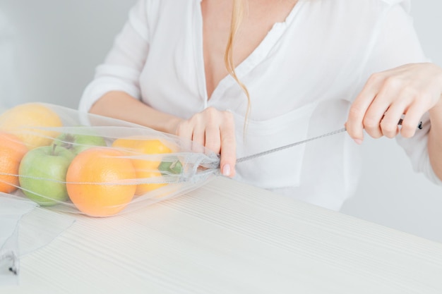 La bella ragazza imballa le verdure e la frutta in una borsa di stoffa riutilizzabile. il concetto di zero rifiuti. tonificante.