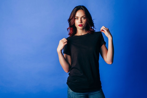 Beautiful young girl in posing in black t-shirt in the studio on blue