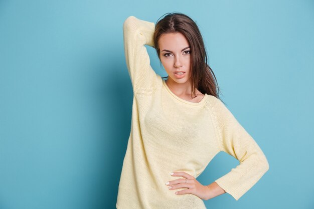 Photo beautiful young girl posing and looking at the camera isolated on the blue background