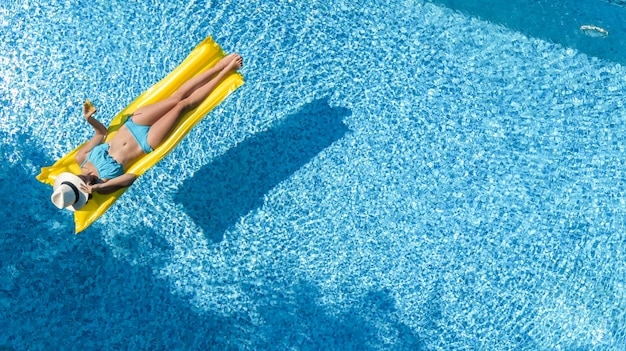 수영장에서 편안한 아름다운 어린 소녀, 풍선 매트리스에서 수영과 가족 휴가, 열대 휴가 리조트, 위에서 공중 무인 항공기보기에 물에 재미가