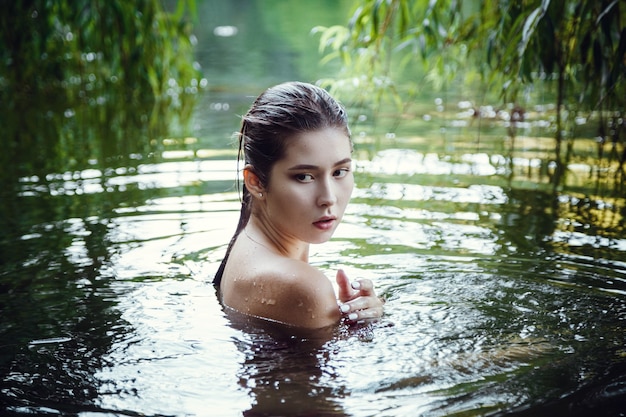 Beautiful young girl resting in water. The woman blindly, floats down the river, meditation in water