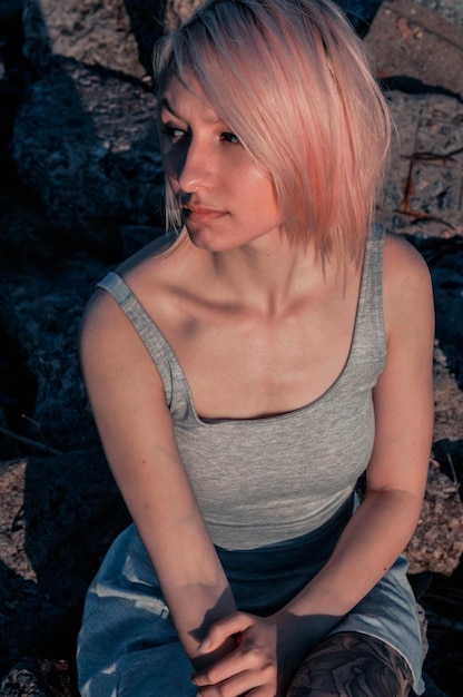 Beautiful young girl in a short dress sits on the stones