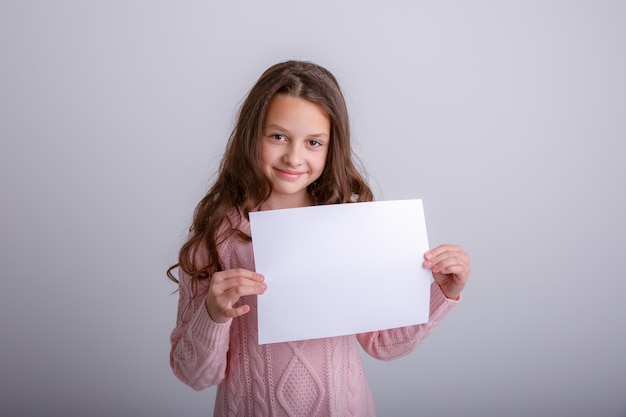 Photo beautiful young girl shows a blank paper sheet