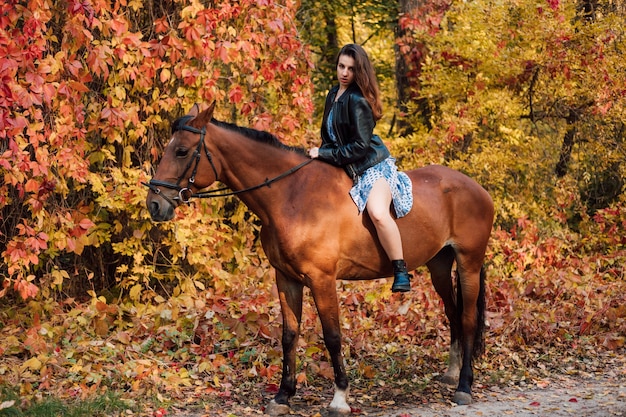 Photo beautiful young girl sits astride a horse in a dress and boots