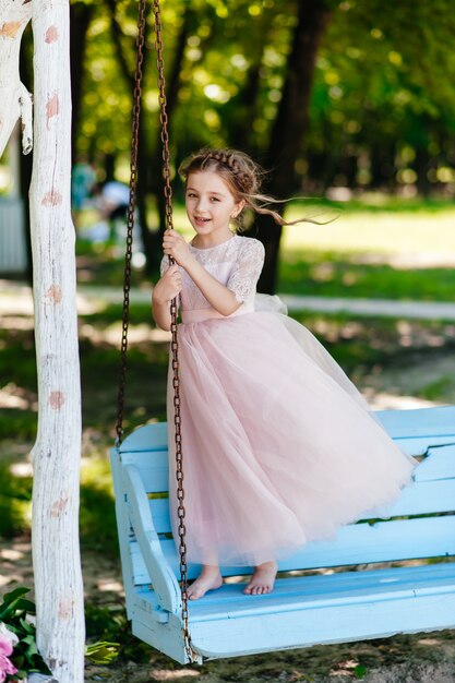 A beautiful young girl sits in the park on a bench.