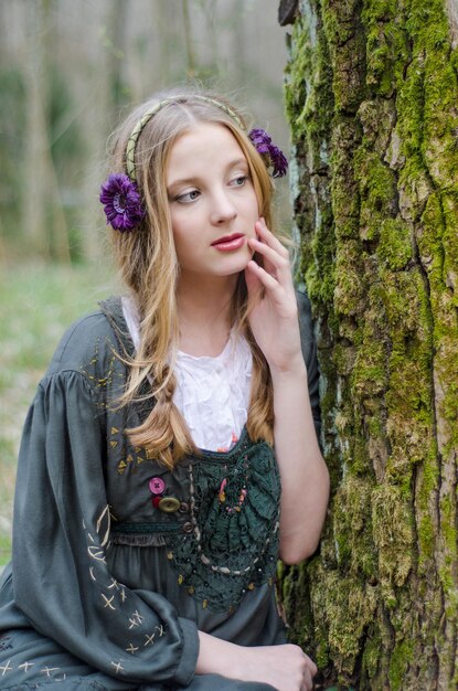 Beautiful young girl sitting near a tree