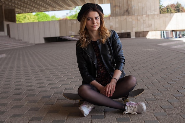 Beautiful young girl sitting on the skateboard