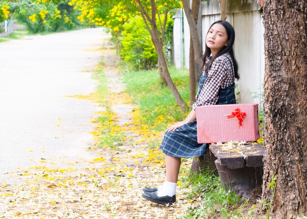 ギフトボックスと木の下に座っている美しい少女。