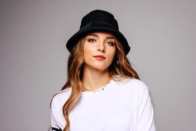 A beautiful young girl smiles easily Model with long hair and blue eyes in a hat on a white background closeup with copy space