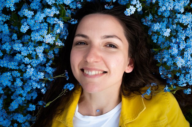 Красивая молодая девушка улыбается на фоне синих цветов.