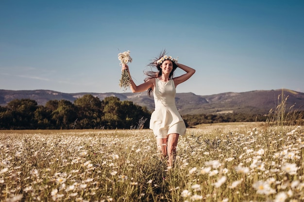 Beautiful young girl smiling over chamomile field Carefree happy brunette woman with healthy long hair having fun outdoor in nature