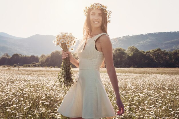 Beautiful young girl smiling over chamomile field Carefree happy brunette woman with healthy long hair having fun outdoor in nature