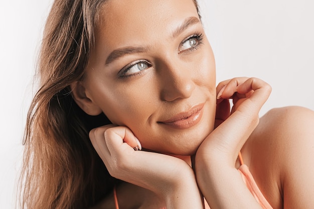 Foto bella ragazza sorridente e in posa guardando la telecamera su uno sfondo bianco isolato. donna castana positiva. sguardo gentile. volto di bellezza.