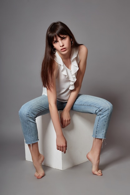 Beautiful young girl smiling sitting on a cube