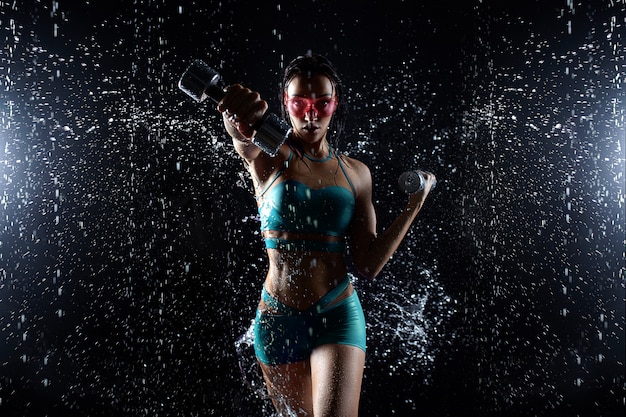 La bella ragazza in abiti sportivi posa con le teste di legno nello studio dell'acqua