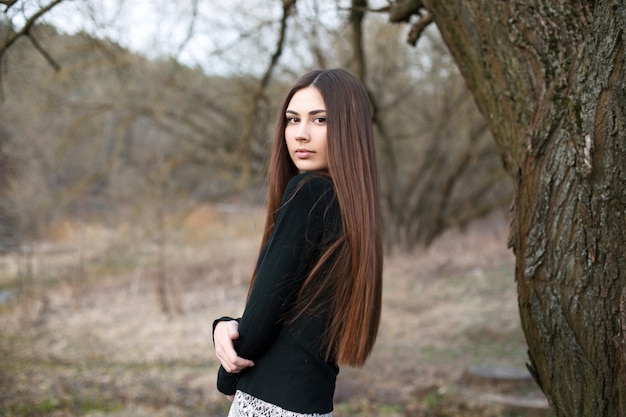 Beautiful young girl standing near a tree in the garden