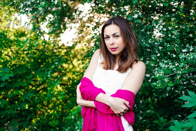 beautiful young girl in the summer in the park at sunset in a dress smiling