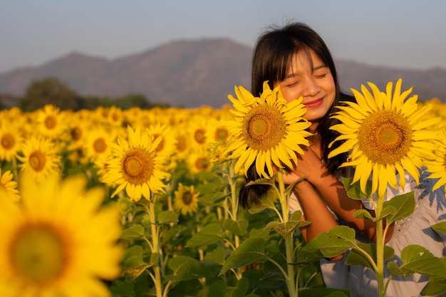 Beautiful young girl at sunflower field with blue sky