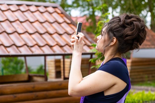 A beautiful young girl takes pictures on the phone Young woman in profile Phone in hand