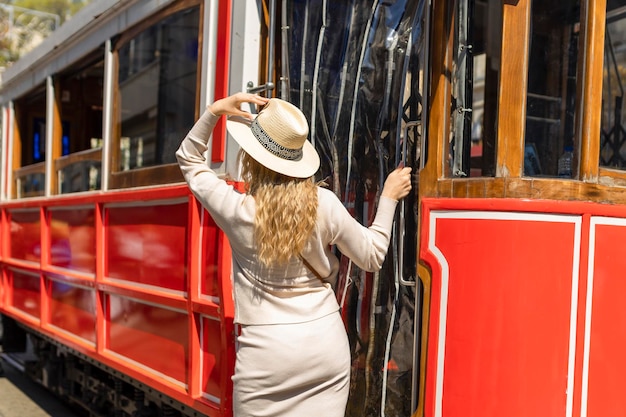 Beautiful young girl tourist in a hat poses in front of tram at popular Istiklal street in Beyoglu Istanbul Turkey