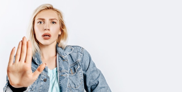 Beautiful young girl unhappy frown and says stop gesture on gray isolated background