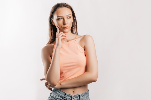 Beautiful young girl unhappy frown and thinks on gray isolated surface