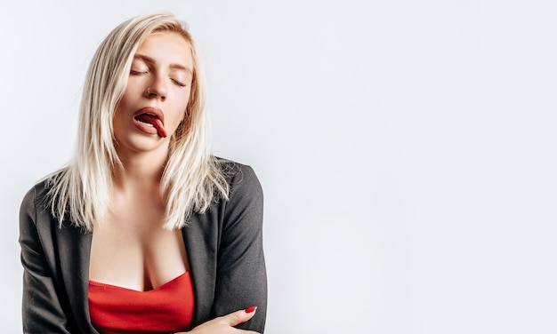 Beautiful young girl unhappy and tired showing tongue on gray isolated background