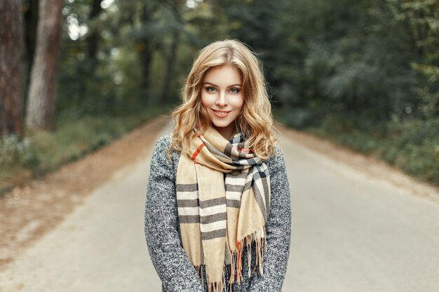 ヴィンテージのスカーフの美しい少女が秋の公園を歩きます。