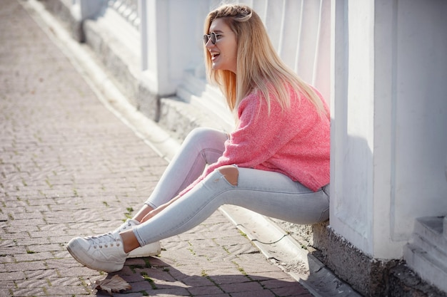 Beautiful young girl on a walk in the autumn city Beautiful woman in a sweater Fashion portrait stylish pretty woman outdoor Young woman having fun in city Street fashion