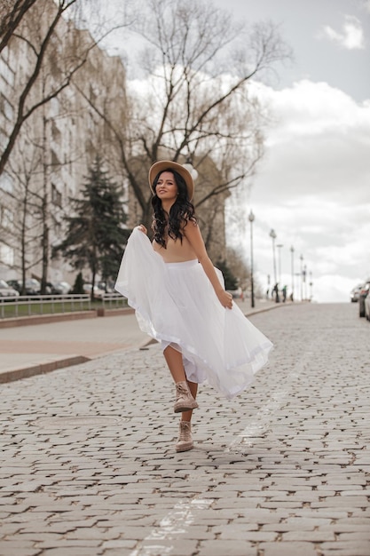 beautiful young girl walking around the city in a white skirt and hat