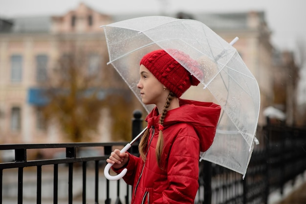 美しい若い女の子が透明な傘を持って雨の中を歩く秋の雰囲気天気