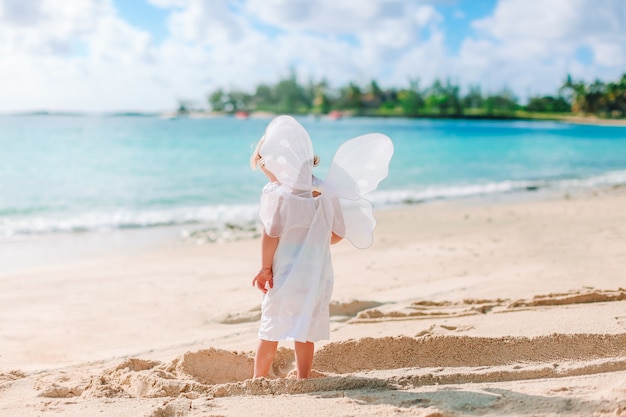 Beautiful young girl wearing angel wings on the beach