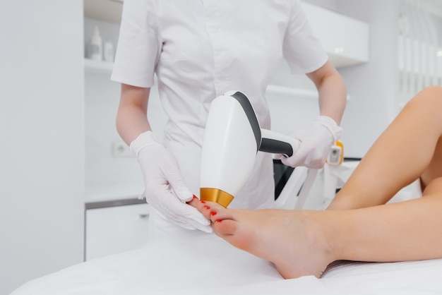 A beautiful young girl will perform a laser hair removal procedure with modern equipment in the Spa salon close-up