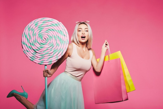 Photo beautiful young girl with blonde hair wearing top and skirt standing with huge sweet lollypops
