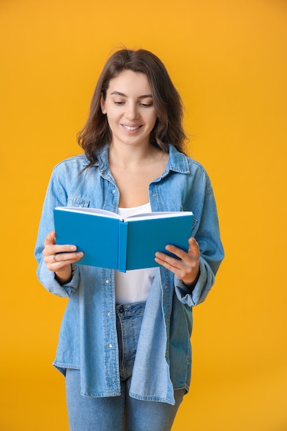 Beautiful young girl with book on color