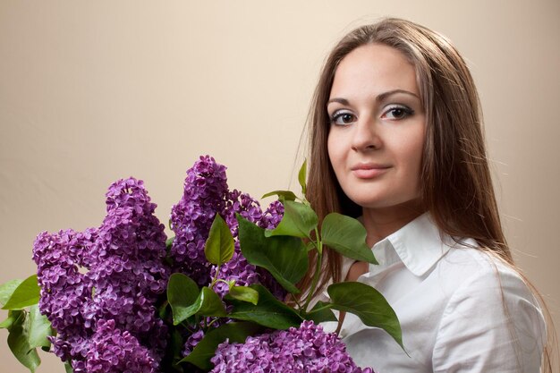 Beautiful young girl with a bouquet of lilac