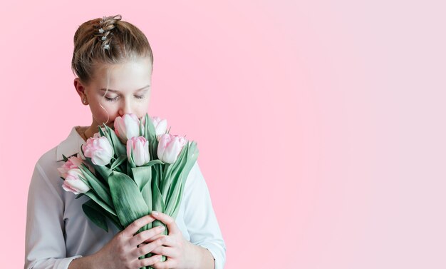 Beautiful young girl with a bunch of pink tulip flowers side view