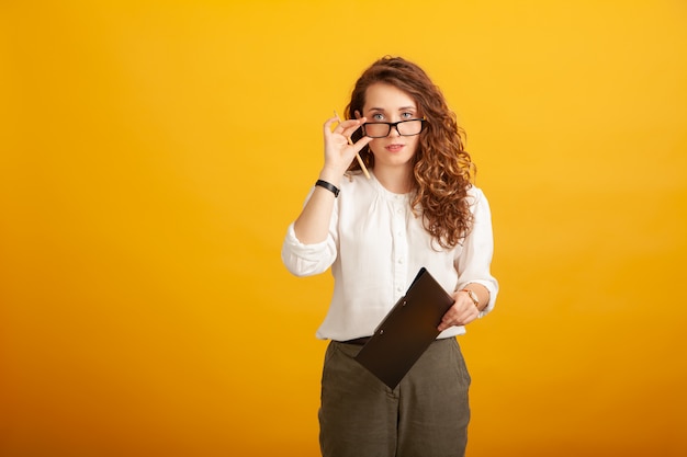 Beautiful young girl with a clipboard and a pencil puts down her glasses