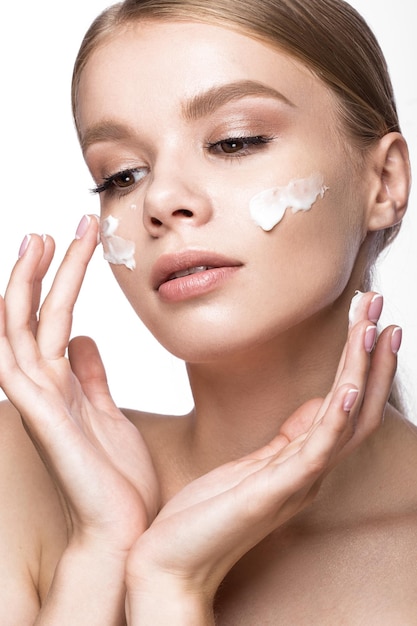 Beautiful young girl with cream on the skin and French manicure. Beauty face. Picture taken in the studio on a white background.